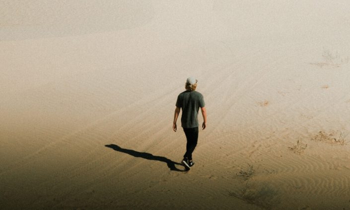 Man walking alone in the desert pondering unanswerable questions