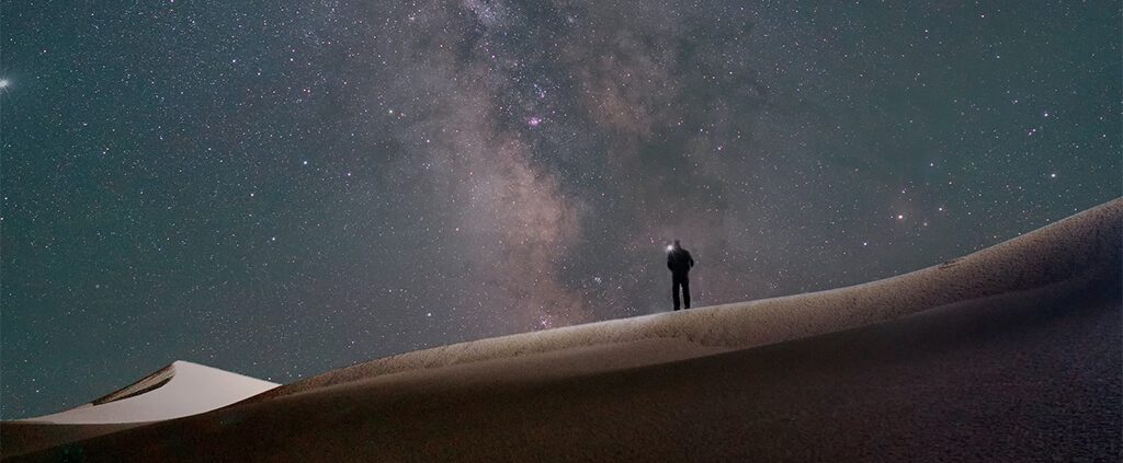Man alone in field with galaxy
