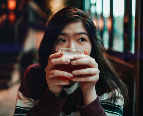 Photo portrait of girl up close holding a coffee cup in front of her face