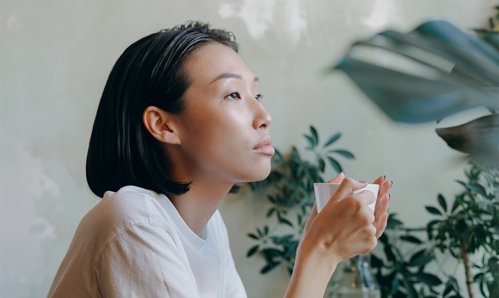 Image of a girl thinking and holding a cup of coffee