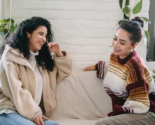 two woman is chatting on a couch